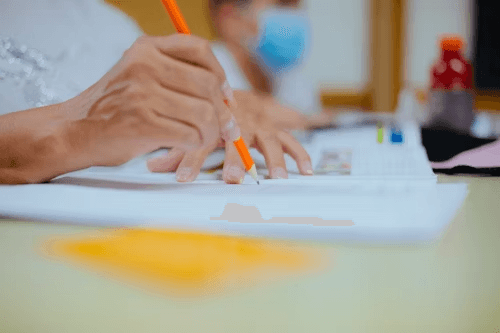 Hands writing on paper with educational materials